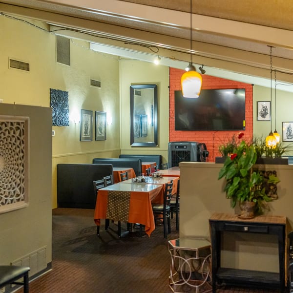 Interior of Tasty Thai Kitchen with tables set, booths, and decorative elements on light green walls.