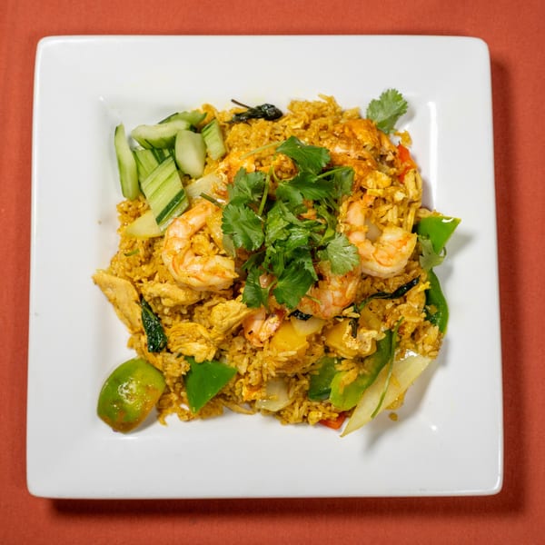 Tasty Thai Kitchen's pineapple fried rice with shrimp, chicken, vegetables, and cilantro on a white plate.