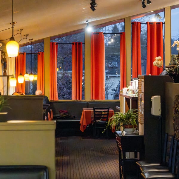 Interior of Tasty Thai Kitchen with red curtains, pendant lights, and a table set for dining.